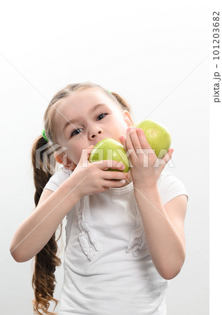 a little girl holds two green apples in her hands on a white background a little girl holds two green apples in her hands on a white background 101203682