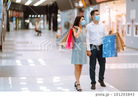 Young couple holding shopping bags, looking upon showcase and discuss shopping inside of mall. 101203843