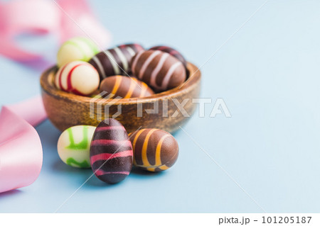 Chocolate easter eggs in bowl on blue background. Chocolate easter eggs in bowl on blue background. 101205187
