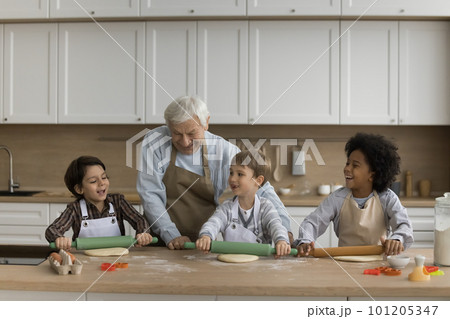Happy grandpa and multiethnic grandsons in aprons preparing cookies 101205347