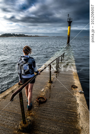Young Woman At The End Of Bridge To Ferry Station To Ile De Batz At City Of Roscoff At The Finistere Atlantic Coast In Brittany, France 101206007