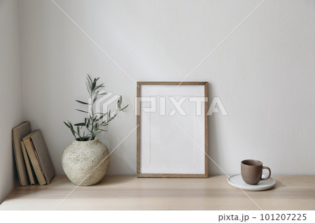 Mediterranean breakfast still life. Cup of coffee, books. Empty wooden picture frame mockup on desk, table. Textured vase with olive branches. Elegant working space, home office. Scandinavian interior Mediterranean breakfast still life. Cup of coffee, books. Empty wooden picture frame mockup on desk, table. Textured vase with olive branches. Elegant working space, home office. Scandinavian interior 101207225