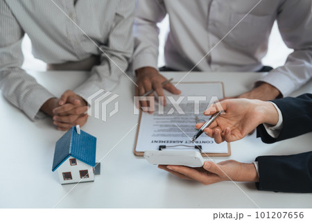 Happy couple signing a contract with real estate agent. renters tenants sign mortgage loan investment agreement or rental insurance contract meeting realtor lender landlord making real estate sale 101207656