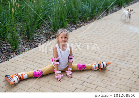A little caucasian girl sits in a transverse twine shod in roller skates. A little caucasian girl sits in a transverse twine shod in roller skates. 101208950