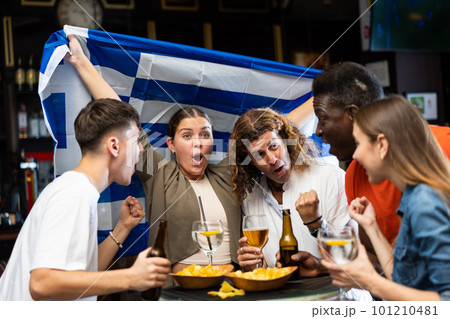 Group of sports fans celebrating victory of favorite team from Greece in bar 101210481