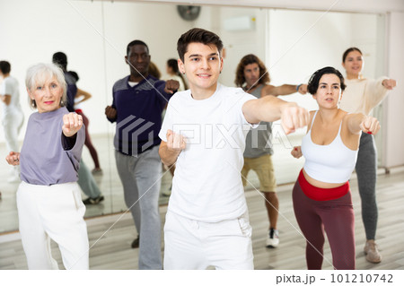 Young guy practicing punches during group self-defence workout Young guy practicing punches during group self-defence workout 101210742