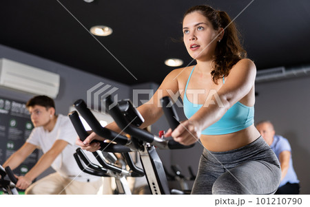 Young girl working out on stationary bicycle in gym 101210790