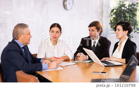 Business partners discussing projects at table in office 101210799