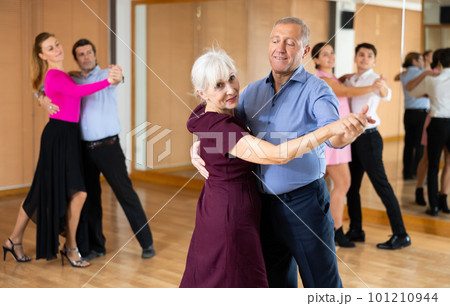 Couple of mature dancers rehearsing ballroom dances in dance studio Couple of mature dancers rehearsing ballroom dances in dance studio 101210944