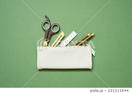 School office writing supplies in pencil case on green desk. top view, copy space 101211644