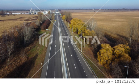 Cars driving along the highway on an autumn sunny day. Automobile road with white markings between agricultural fields. View of the cars driving on paved road. automobile vehicles. Aerial drone view. Cars driving along the highway on an autumn sunny day. Automobile road with white markings between agricultural fields. View of the cars driving on paved road. automobile vehicles. Aerial drone view. 101212270