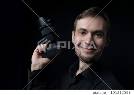 Low key portrait of a professional photographer smiling man with dslr camera 101212598