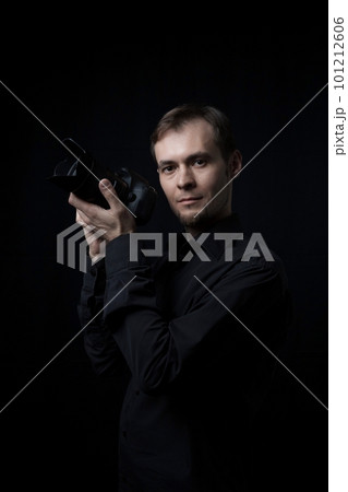 Low key portrait of photographer man with a photo camera in the dark, copy space 101212606
