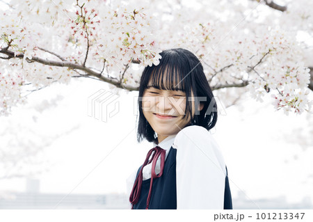 桜の下で笑顔を見せる女子高生 101213347