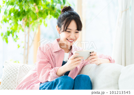 リビングでスマホを見る若い女性 リビングでスマホを見る若い女性 101213545