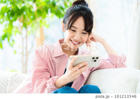 リビングでスマホを見る若い女性 101213546