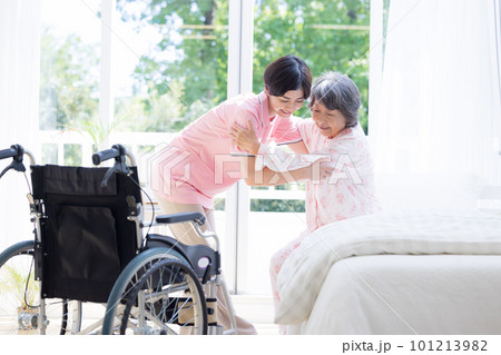 介護 ベットから起きあがるシニアを介助する介護士 介護 ベットから起きあがるシニアを介助する介護士 101213982