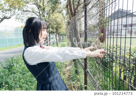 フェンスの前で応援する女子高生 101214773