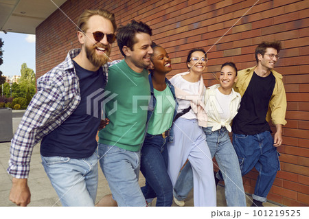 Cheerful carefree group of friends in casual clothes are happily walking down street. 101219525