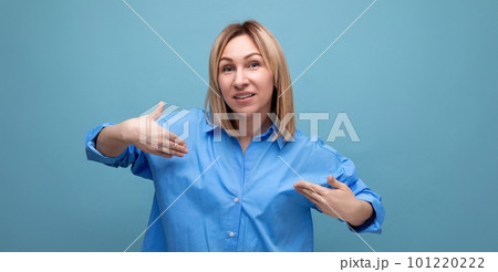 confident blond young millennial in casual shirt showing off her look on blue background with copy 101220222