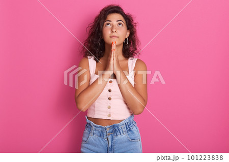 Horizontal shot of good looking girl dressed casually, keeping palms pressed together in front of her, having bad mood, begging for forgiveness. Human facial expressions, emotions and body language. 101223838