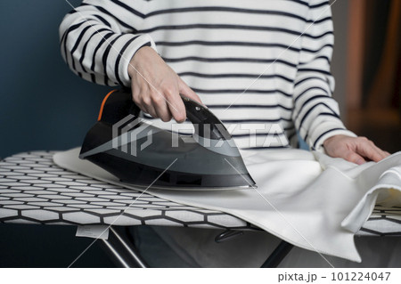Woman irons clothes on an ironing board in the laundry room at home close-up Woman irons clothes on an ironing board in the laundry room at home close-up 101224047