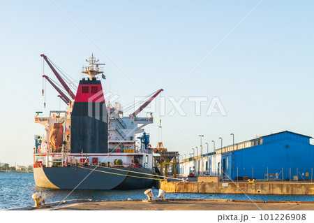 Cargo ship with cranes docked in industrial port 101226908