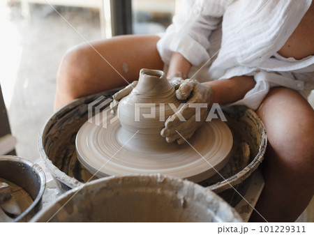 A young ceramist woman sits behind a potter's wheel, Handicraft A young ceramist woman sits behind a potter's wheel, Handicraft 101229311