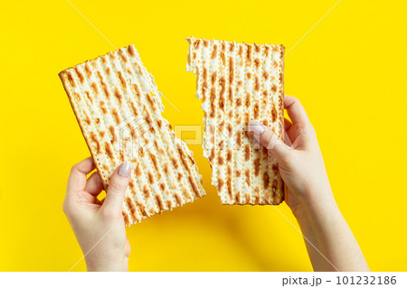 Woman is holding matzah. Celebrating the traditional Jewish holiday of Passover or Pesach. Matzo on yellow background. 101232186