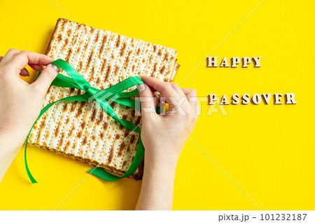Woman is holding matzah. Celebrating the traditional Jewish holiday of Passover or Pesach. Matzo on yellow background. 101232187