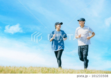 青空の下でジョギングをする笑顔の日本人男女 101233508