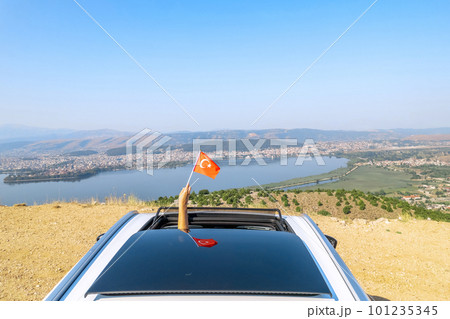 Woman holding Turkey flag from the open car sunroof,  window driving along the serpentine road in the mountains. Top view. Concept 101235345
