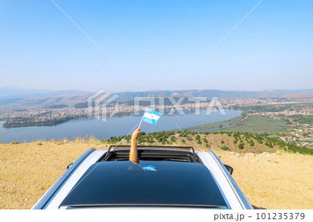 Woman holding Argentina flag from the open car sunroof, window driving along the serpentine road in the mountains. Top view. Concept Woman holding Argentina flag from the open car sunroof, window driving along the serpentine road in the mountains. Top view. Concept 101235379