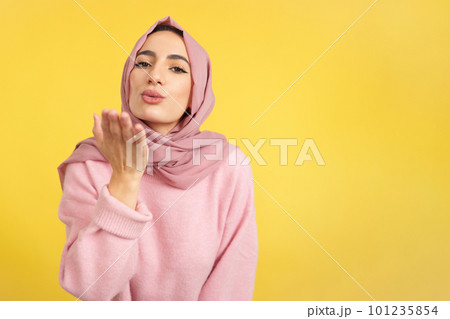 Muslim woman blowing a kiss while looking at the camera Muslim woman blowing a kiss while looking at the camera 101235854