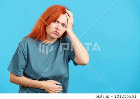 Mature redheaded woman gesturing bodily discomfort and headache 101235861