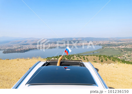 Woman holding Russia flag from the open car sunroof,  window driving along the serpentine road in the mountains. Top view. Concept 101236150