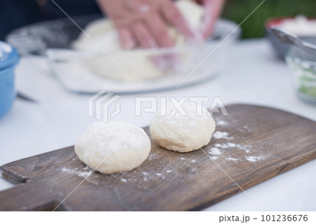 Close up of old female cook taking, holding dough, putting on wooden board, dusting with flour. Concept of fast food. Close up of old female cook taking, holding dough, putting on wooden board, dusting with flour. Concept of fast food. 101236676