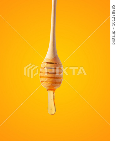 Flowing drops of yellow honey from a wooden stick on a yellow background Flowing drops of yellow honey from a wooden stick on a yellow background 101238885