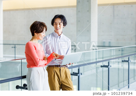 オフィスでパソコンを見ながら打ち合わせする男女 101239734