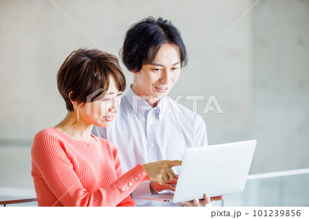 オフィスでパソコンを見ながら打ち合わせする男女 101239856