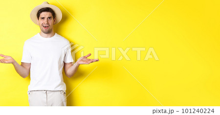 Concept of tourism and summer. Confused guy traveller shrugging, cant understand something, standing against yellow background 101240224