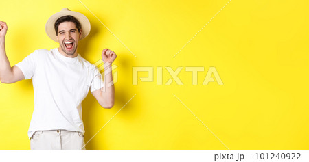 Concept of tourism and lifestyle. Happy man tourist celebrating, rejoicing over vacation, standing over yellow background Concept of tourism and lifestyle. Happy man tourist celebrating, rejoicing over vacation, standing over yellow background 101240922