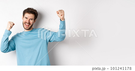 Image of happy young man triumphing, feeling like champion, winning and screaming in cheer, standing over white background Image of happy young man triumphing, feeling like champion, winning and screaming in cheer, standing over white background 101241178