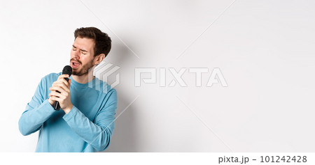 Romantic man singing song in microphone at karaoke, standing over white background Romantic man singing song in microphone at karaoke, standing over white background 101242428