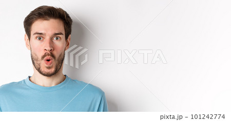Close-up of surprised man face, saying wow and staring at camera amazed, standing on white background 101242774