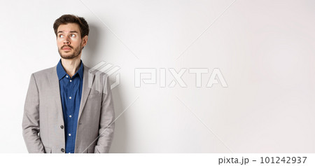 Thoughtful sad businessman in suit looking at upper left corner logo, thinking or spacing out, standing on white background Thoughtful sad businessman in suit looking at upper left corner logo, thinking or spacing out, standing on white background 101242937