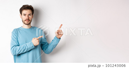 Portrait of serious caucasian man with beard pointing right at logo and looking at camera, standing in casual clothes on white background Portrait of serious caucasian man with beard pointing right at logo and looking at camera, standing in casual clothes on white background 101243006