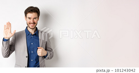 Smiling handsome businessman in suit waving hand, greeting friend with friendly face, say hellp, standing on white background 101243042