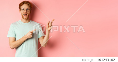 Amazed redhead man in glasses and t-shirt showing special promotion, pointing fingers at upper right corner and staring excited at camera, standing over pink background Amazed redhead man in glasses and t-shirt showing special promotion, pointing fingers at upper right corner and staring excited at camera, standing over pink background 101243102