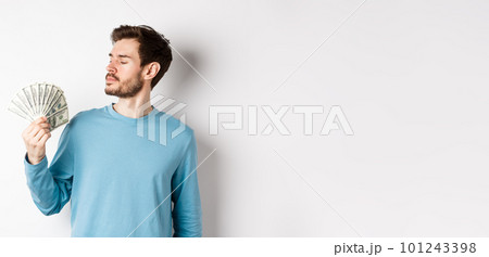 Handsome rich man with beard looking at money, got quick loan, standing over white background Handsome rich man with beard looking at money, got quick loan, standing over white background 101243398